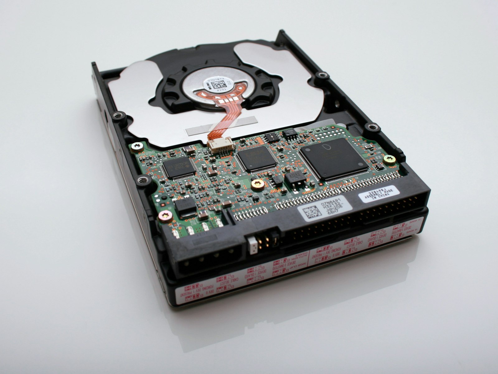 An opened hard drive exposing its platter and controller board, the kind of data-bearing device that must be correctly identified at ITAD intake.