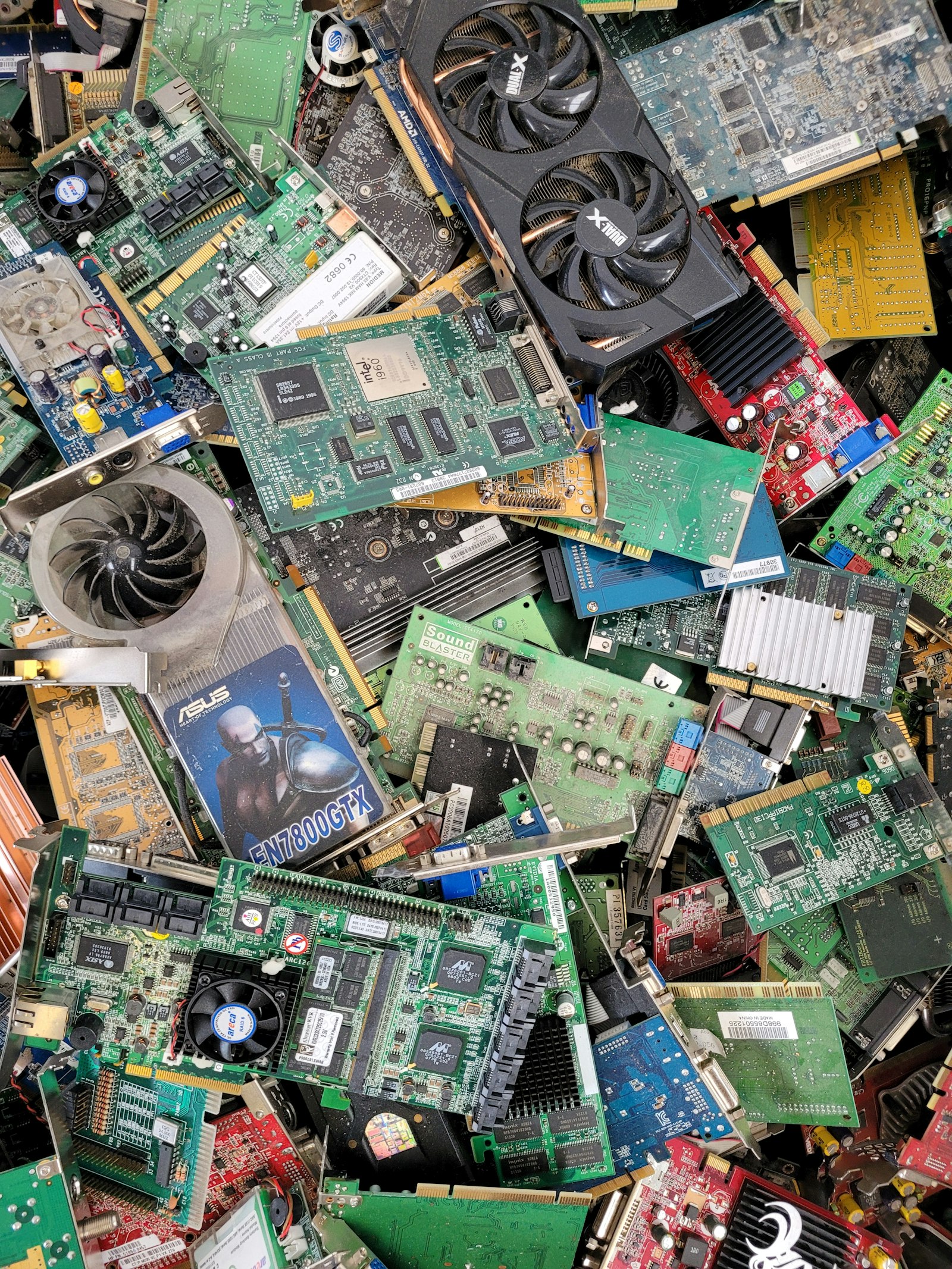 A stack of graphics cards and motherboards at a landfill, hardware whose recovered value depends on real-time IT asset pricing.
